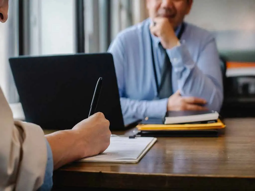 An employee writing notes with a manager