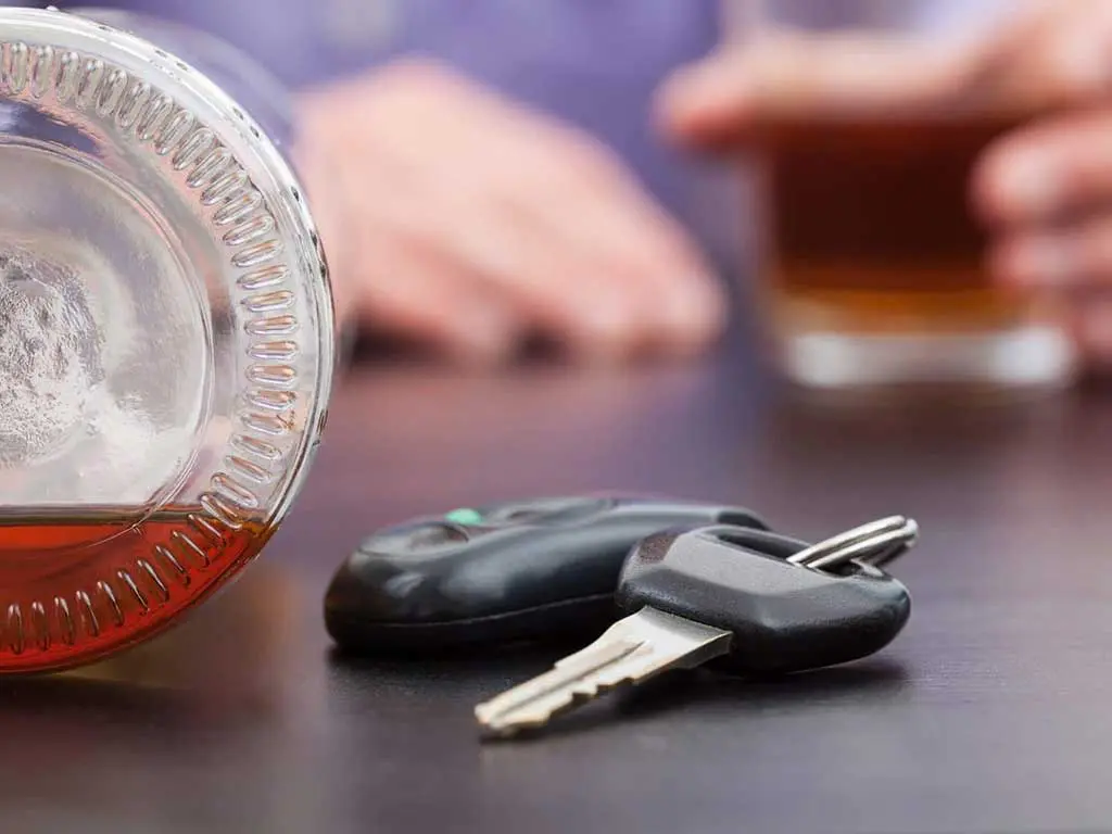 A bottle of alcohol and car key on the table