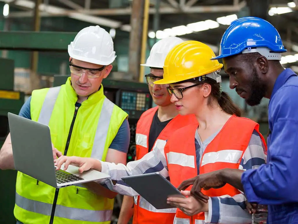Employees wearing safety equipment while using a laptop
