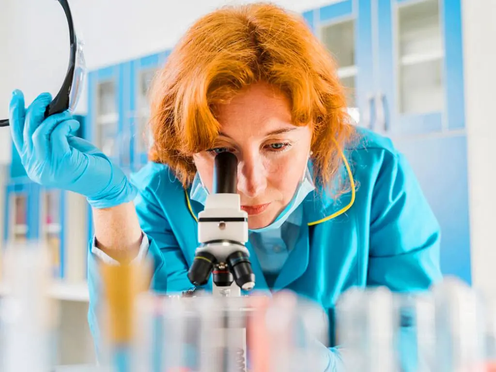 A lab technician using a microscope