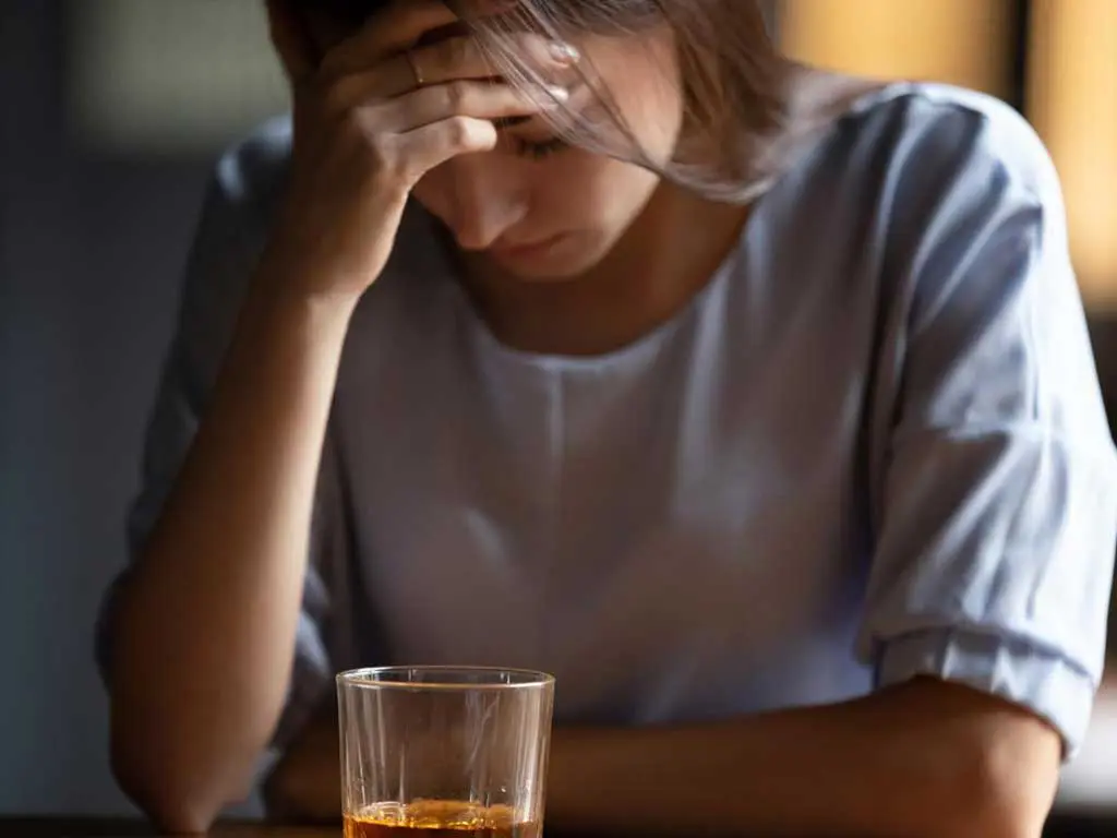 alcohol test positive A woman looking distressed with a glass of alcohol in front of her