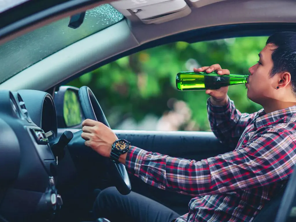 A man drinking alcohol while driving