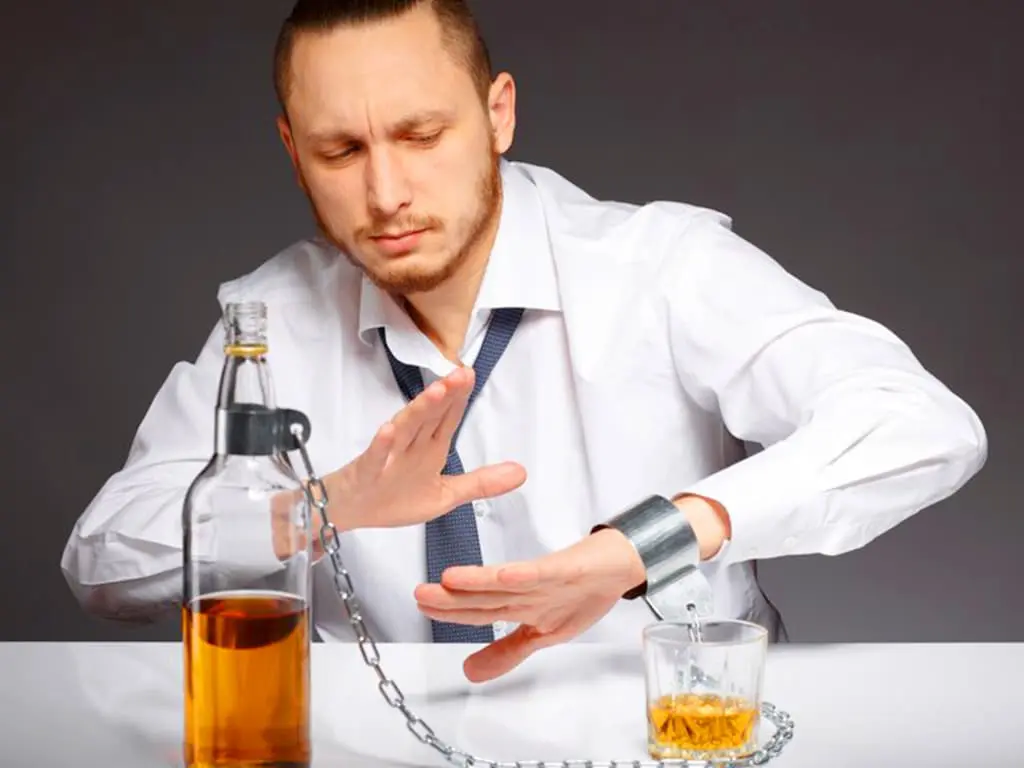 A man wearing a cuffs is refusing to drink alcohol
