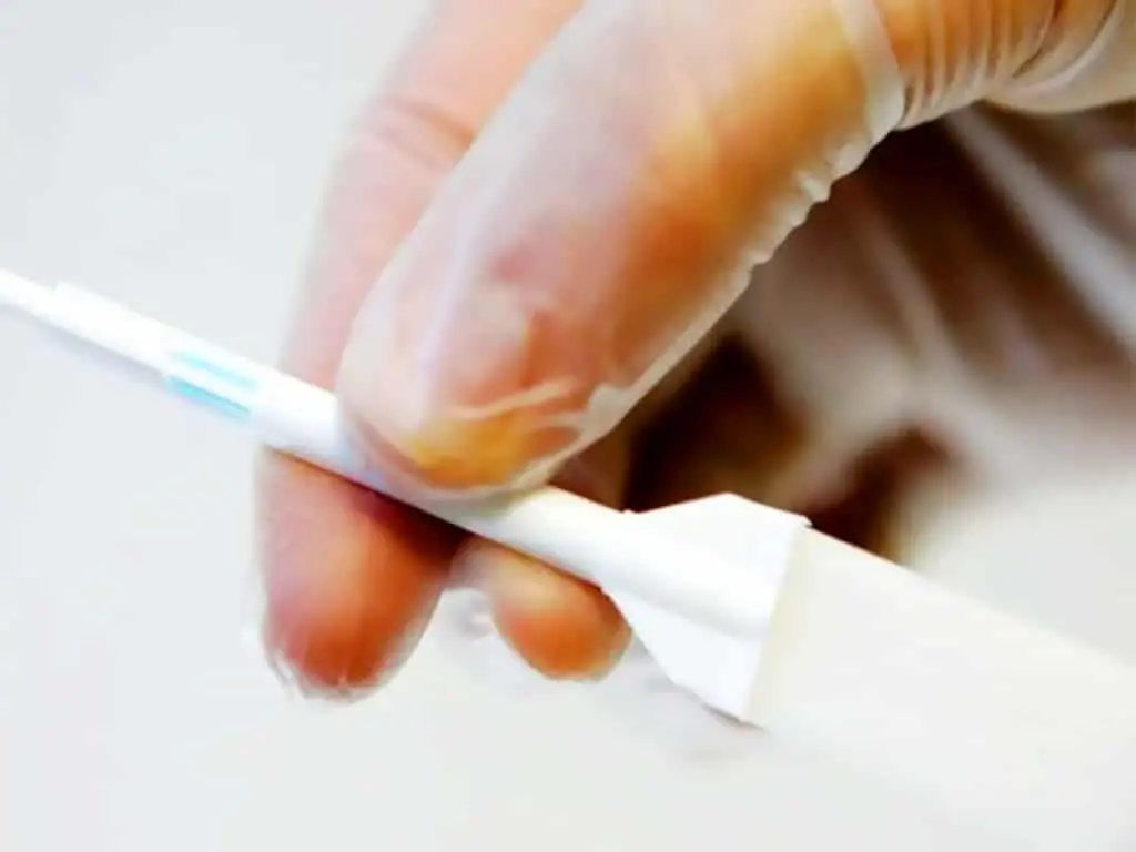 A person holding a saliva collection stick