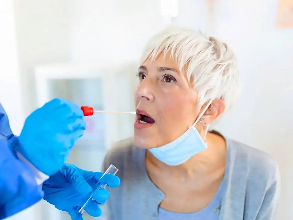 A professional conducting a saliva test on a woman