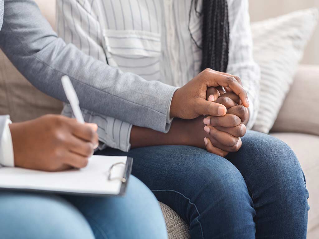 A person holding hands and writing on a clipboard