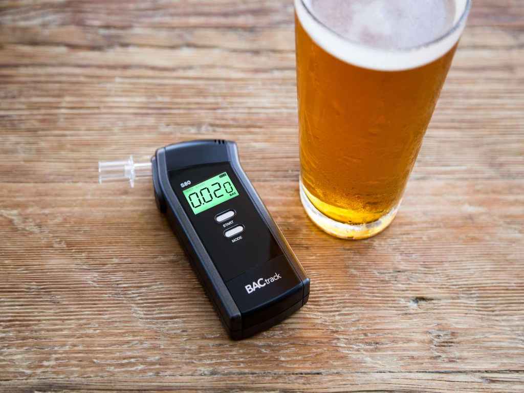 drunk tester BACtrack breathalyser and a glass of beer on the table