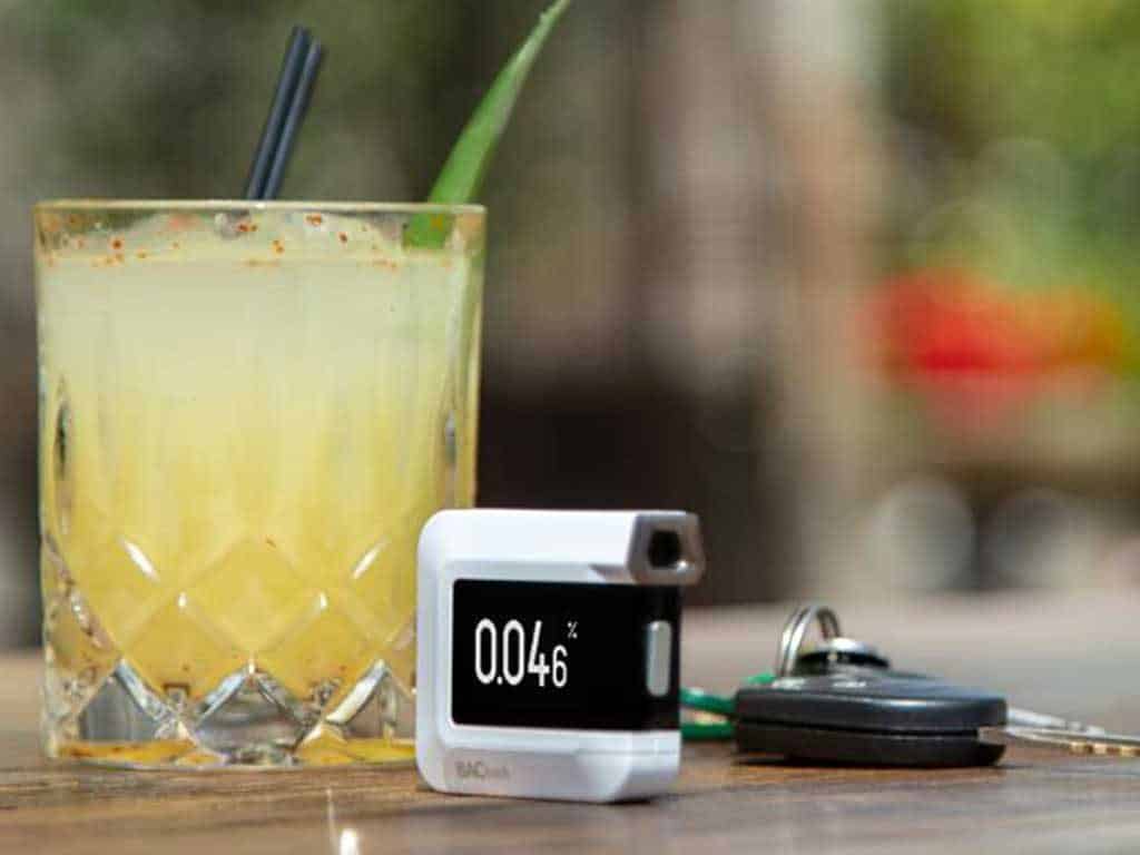 A breathalyser on the table with a glass of drink and keys