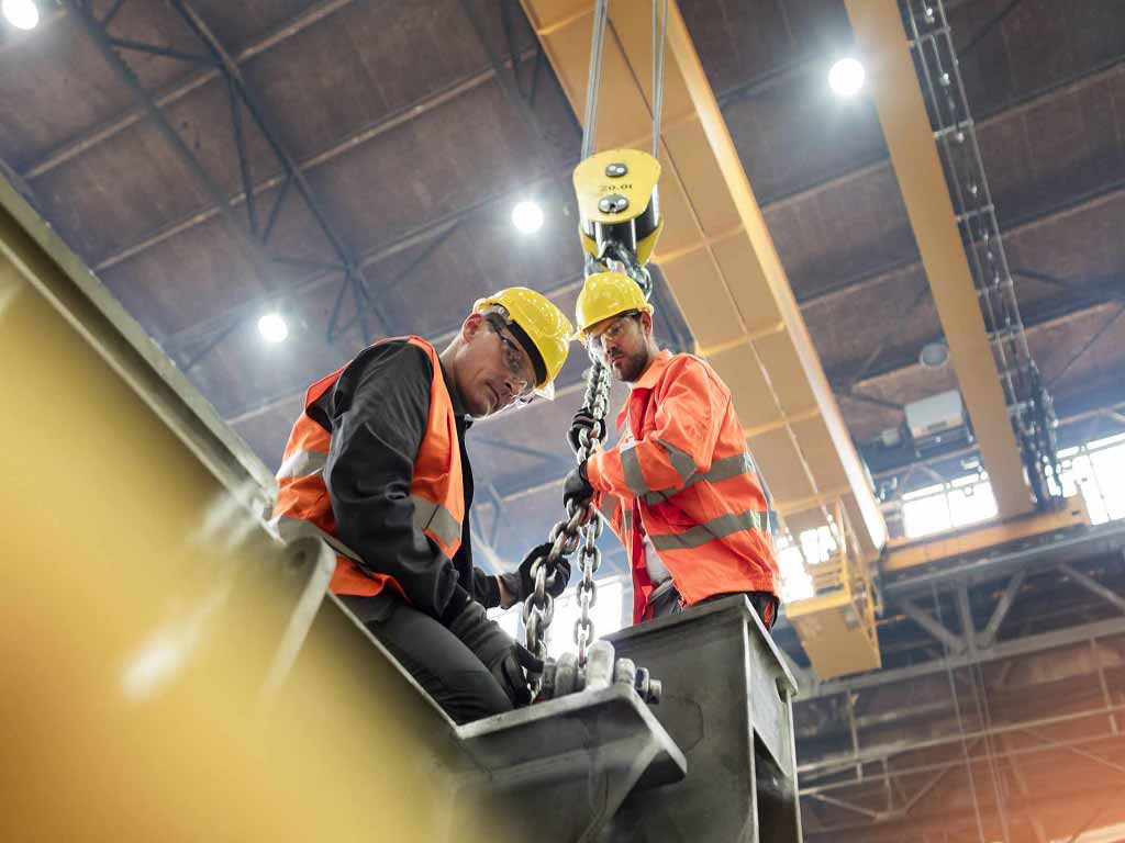 Two construction workers lifting a metal using an equipment