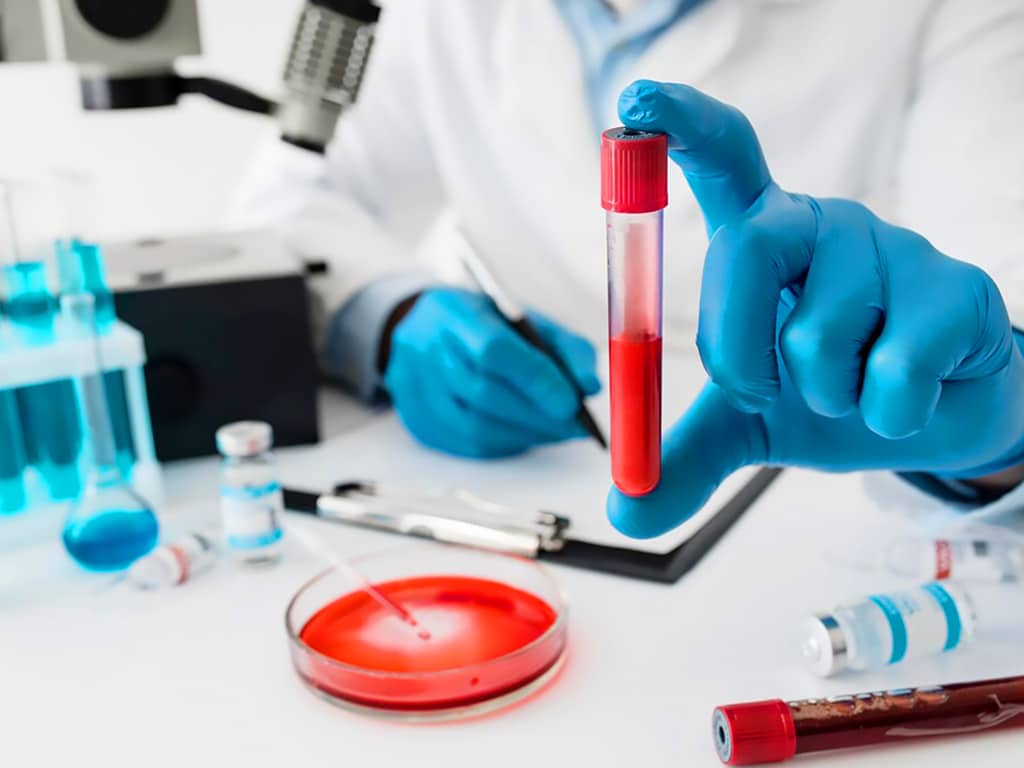 A lab professional holding a tube of blood