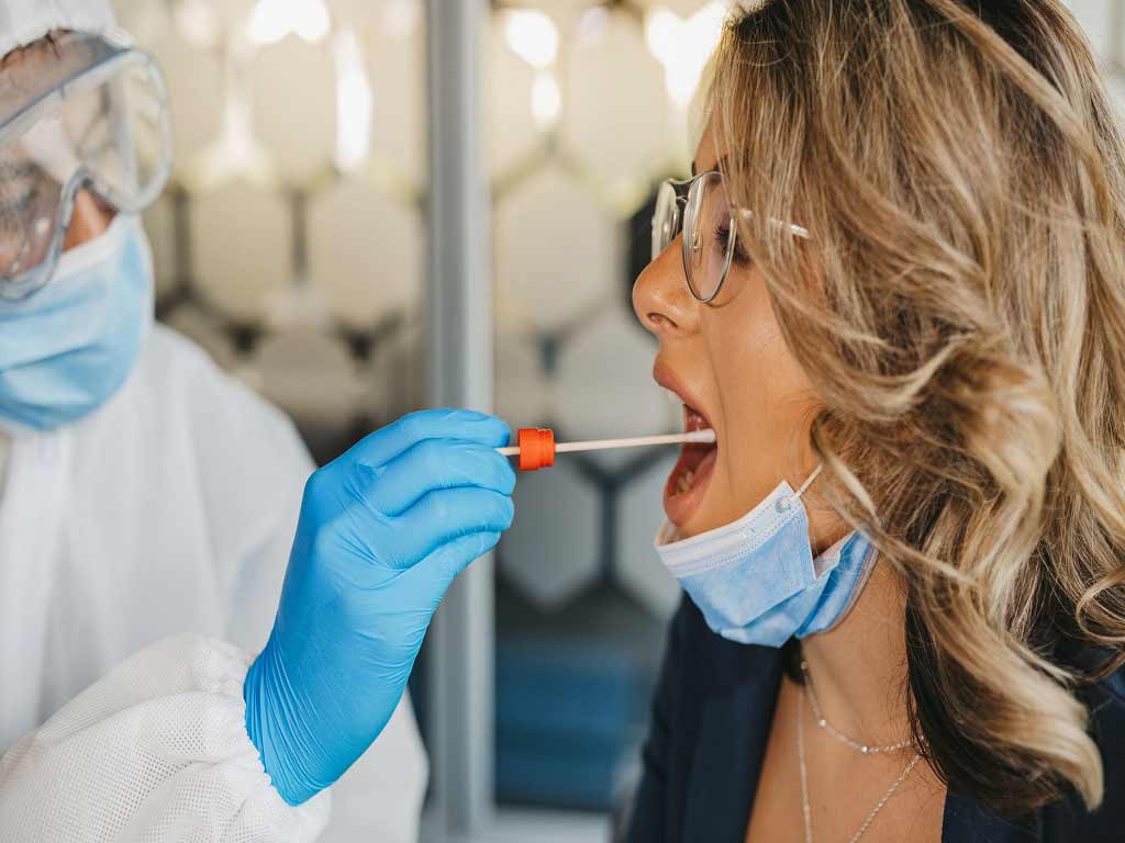 A healthcare professional conducting a saliva test on a female patient