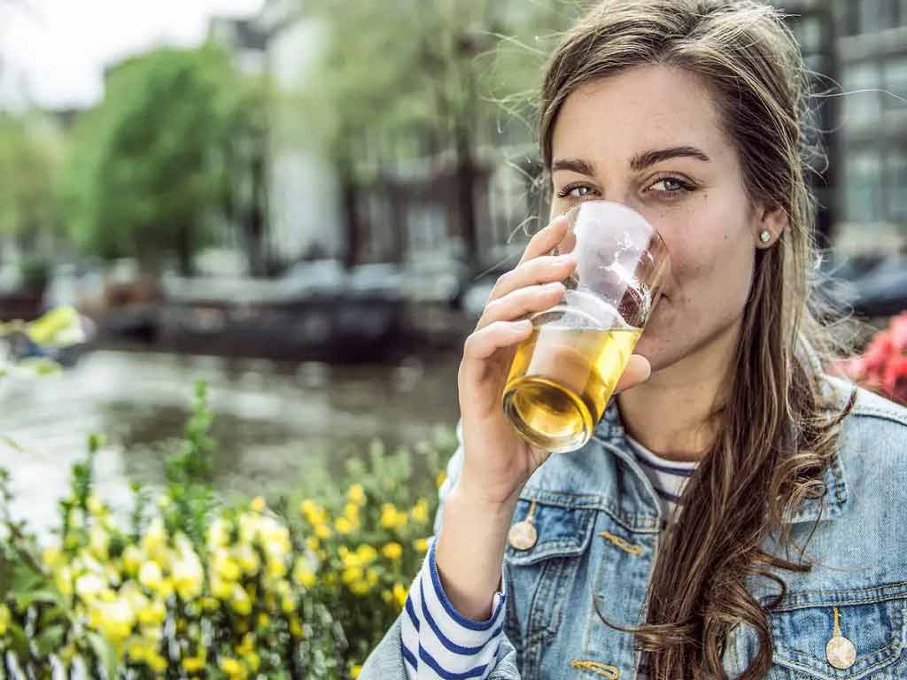 A woman drinking alcohol at a park