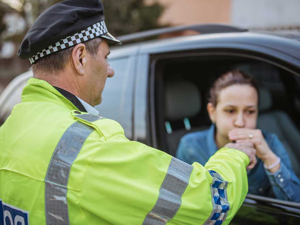 drink driving. 2 A police officer conducting a breath test on a female driver