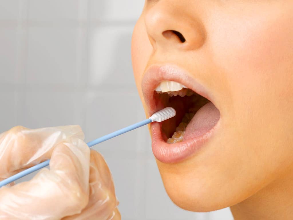 A professional using a mouth swab stick to conduct an oral drug test
