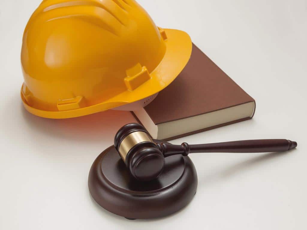 A hard hat, a book, and a gavel on a sound block