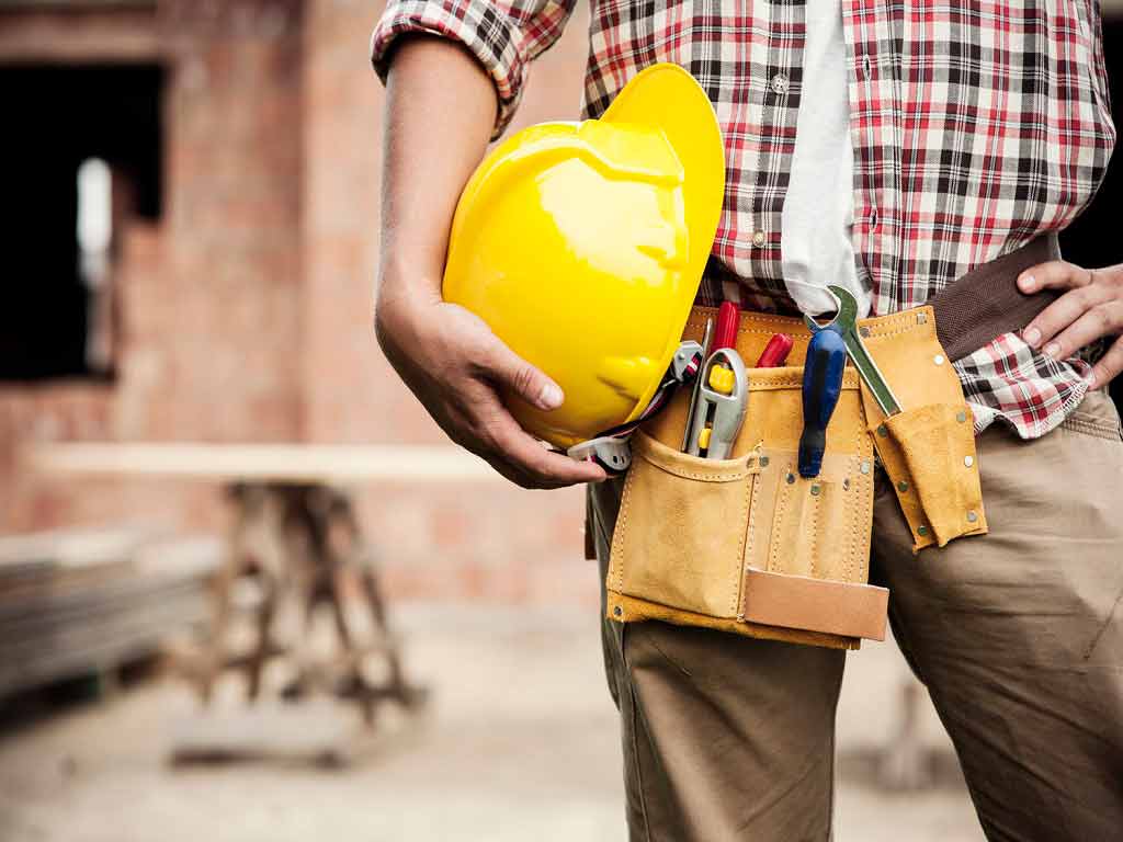 A worker holding a hard hat while on the job