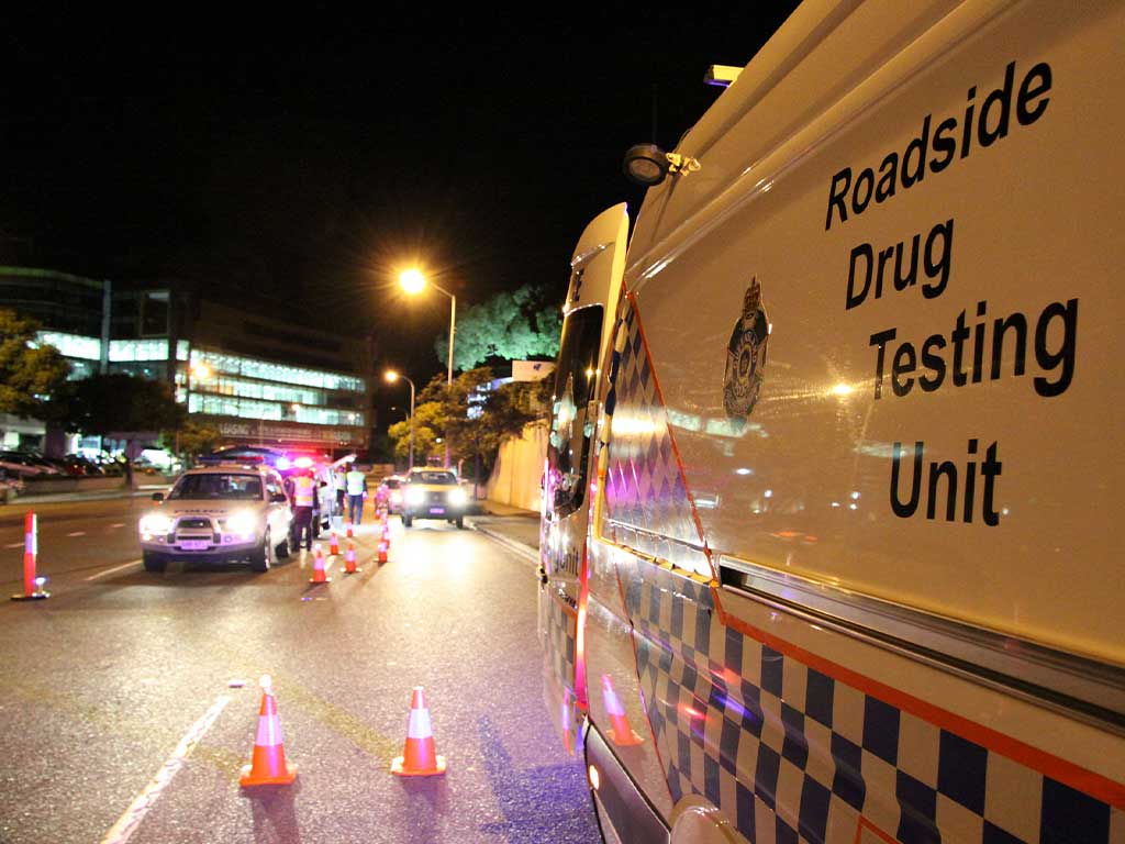 A mobile drug testing unit parked at a roadside at night