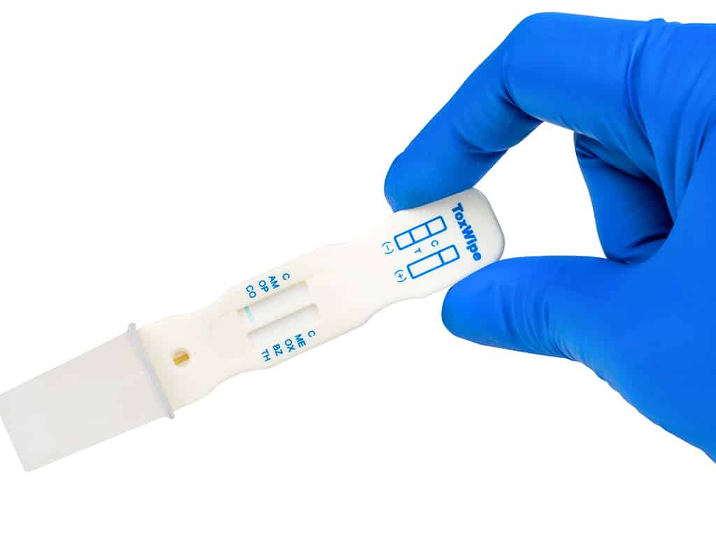 A hand holding the ToxWipe 7 saliva drug test kit