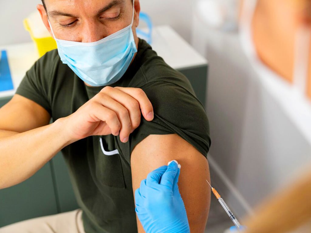 A medical professional sanitising the man's arm before collecting blood samples