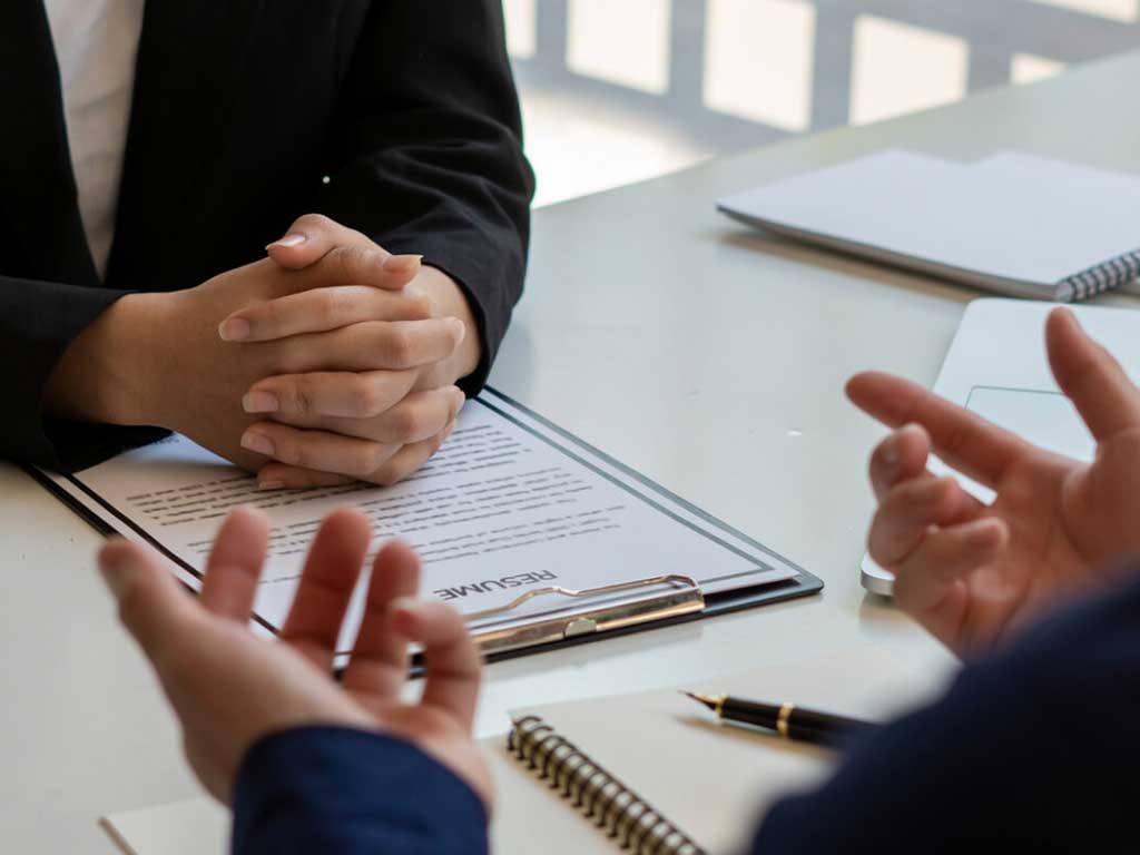 A ongoing job interview with a resume, notebook, and pen on the table