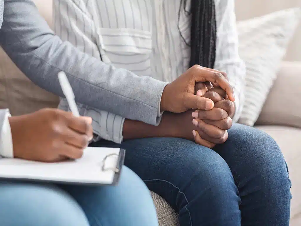 A medical professional touching the arm of her patient while writing notes
