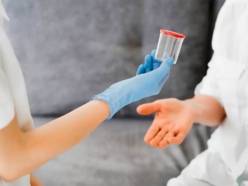 A lab technician giving an empty collection container to a patient