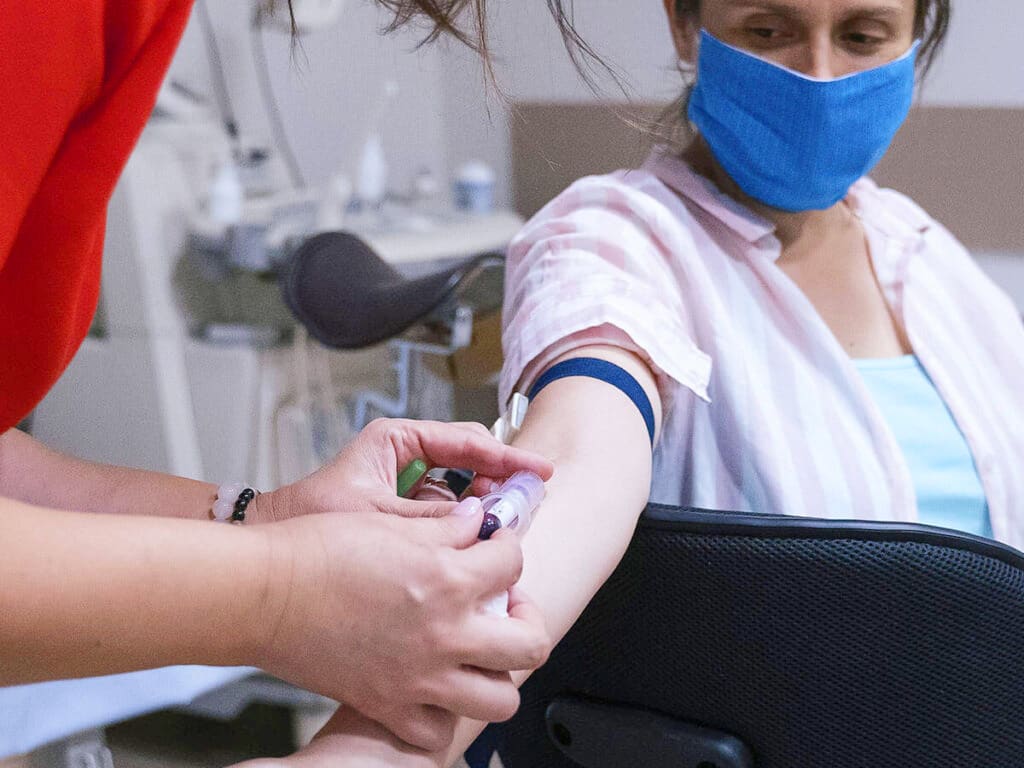 A professional collecting a blood sample from the arm of a patient